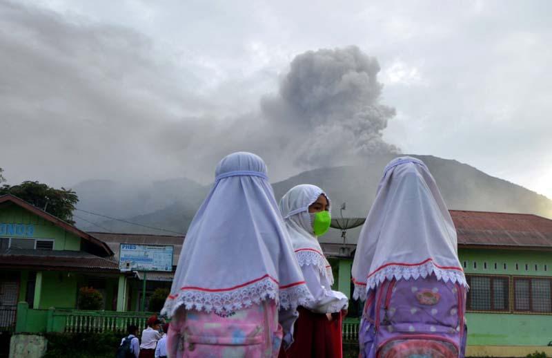 دانش‌آموزان دختر مدرسه‌ای در آگام اندونزی روبروی خاکسترپاشی کوه اتشفشان؛ منبع عکس: Reuters؛ عکاس: Antara Foto