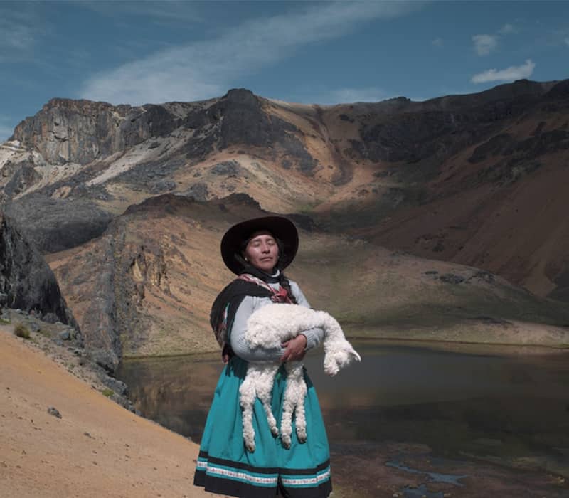 زنی بومی با بزی در آغوش در میان کوه ها