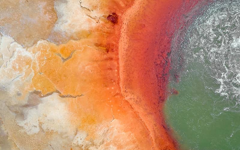 عکس هوایی از دریاچه ای سبزرنگ با لبه های نارنجی
