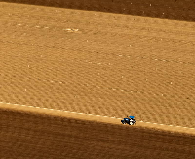 عکس هوایی از عبور خودرویی از کنار مزارع کشاورزی