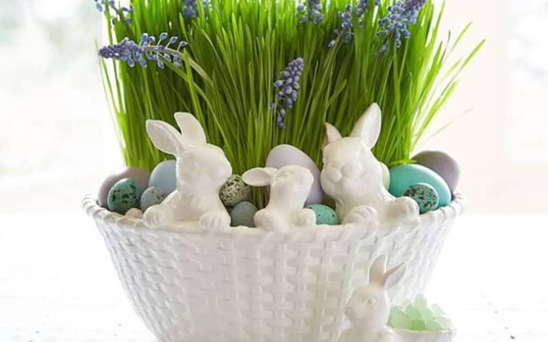 تخم مرغ های رنگی در ظرف سبزه و کنار خرگوش های سرامیکی
