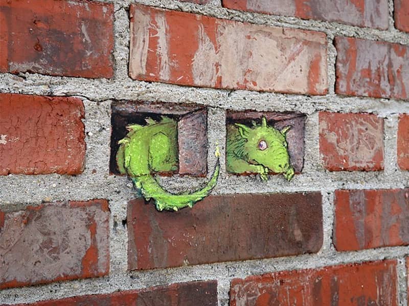 نقاشی سه بعدی حیوانی سبزرنگ در دیوار آجری