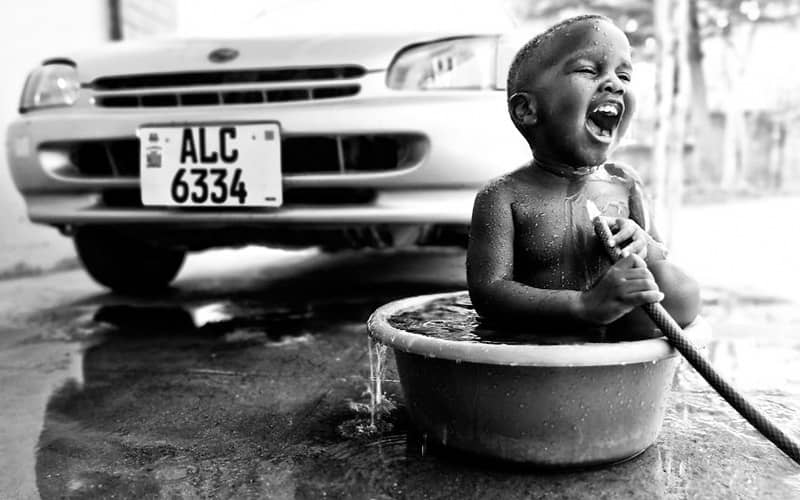 کودکی در حال آب بازی در تشت آب