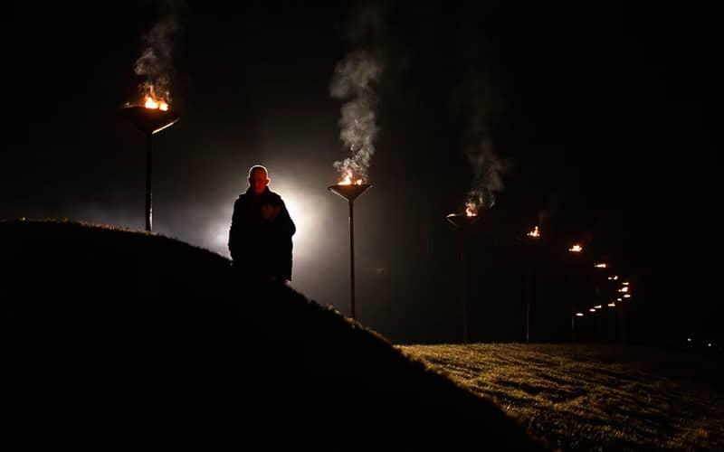 مردی در شب تاریک در حال حرکت از میان مشعل ها