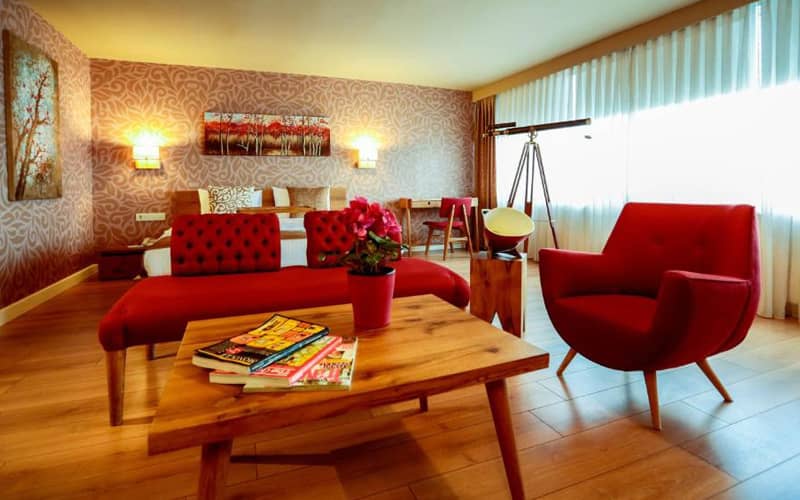 اتاقی با مبلمان قرمز و کف پارکت در هتل ملک مودا
