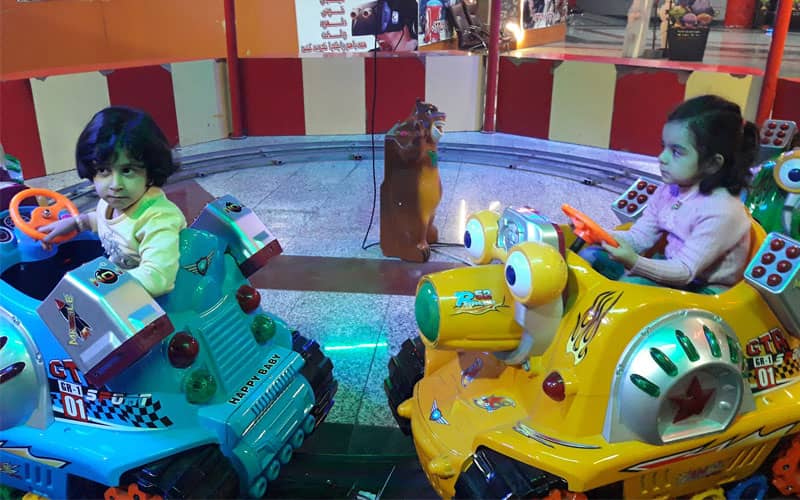 دو کودک مشغول ماشین بازی در سرزمین بازی ها