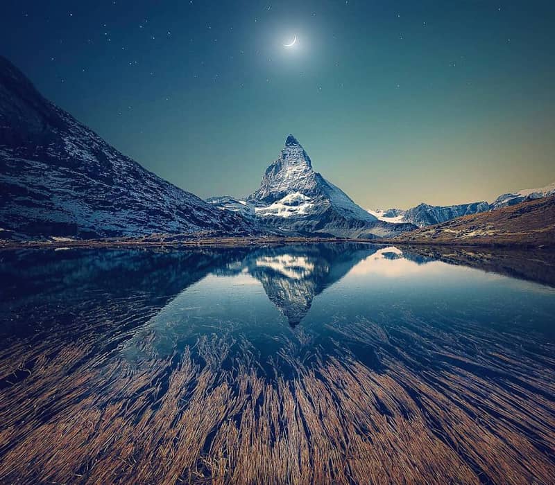 انعکاس تصویر یک کوه در دریاچه زیر نور ماه