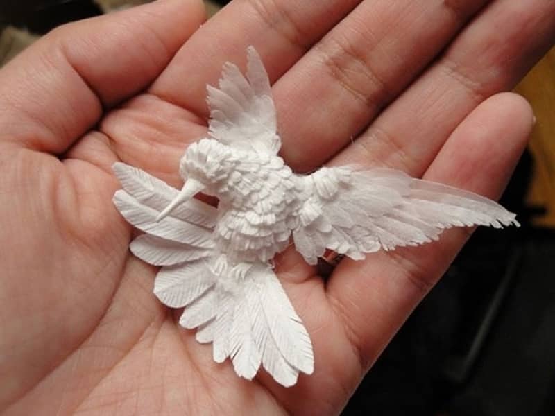 پرنده کاغذی کوچکی در دست هنرمند سازنده اش