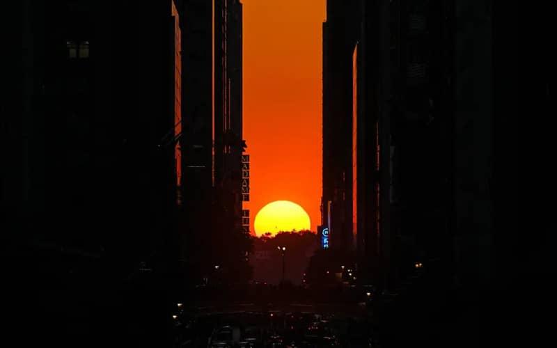 تصویر غروب خورشید از میان ساختمان های شهر