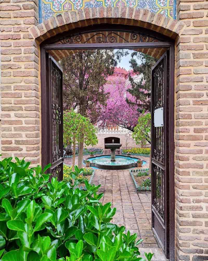 در چوبی ورودی خانه موزه مقدم با گل های بنفش و سبزه های زیبا