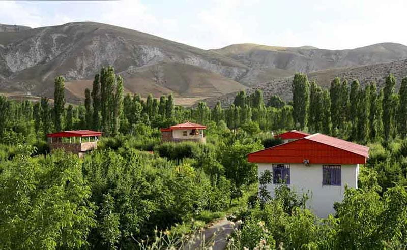خانه های ییلاقی با سقف شیروانی قرمز در روستای کردان میان درختان سرسبز