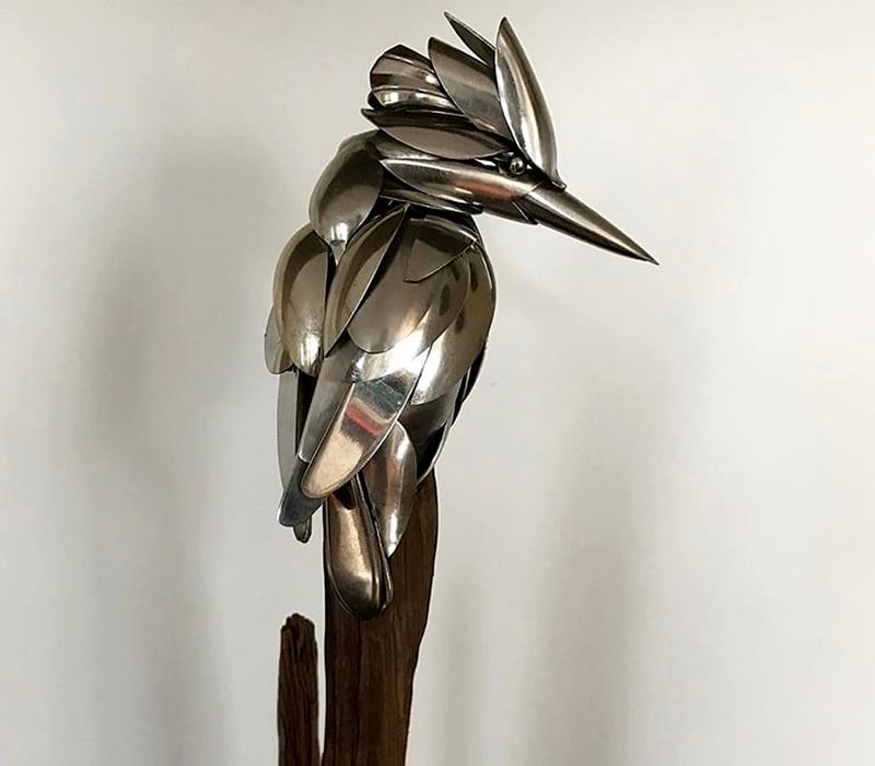 پرنده فلزی روی تنه درخت