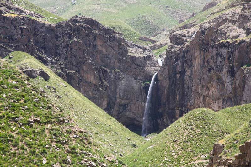 آبشار خور در دامنه صخره ای کوهستان از نمای دور