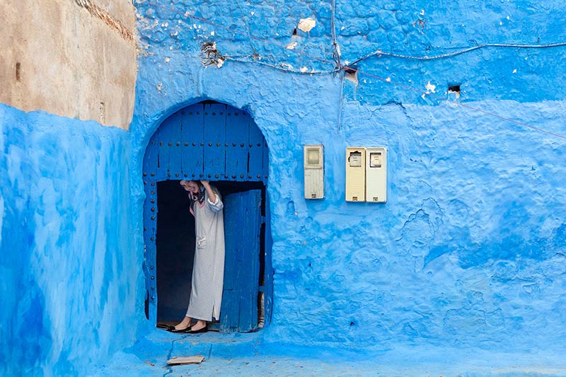 زنی در آستانه یک درب آبی در شهر شفشاون مراکش