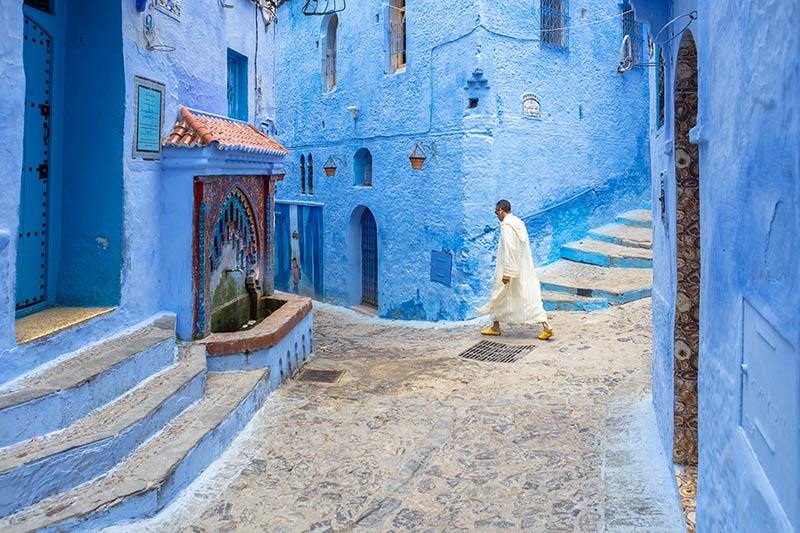 عبور مردی با ردای سفید از کوچه‌های شهر شفشاون مراکش