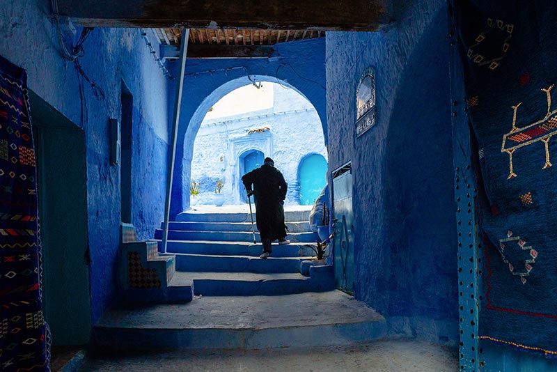 عبور پیرمردی با عصا از دالان‌های شهر شفشاون مراکش
