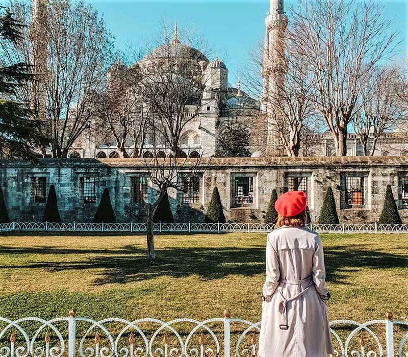 زنی با کلاه قرمز مقابل مسجد آبی استانبول، منبع عکس: andoreia.com، عکاس: ناشناس