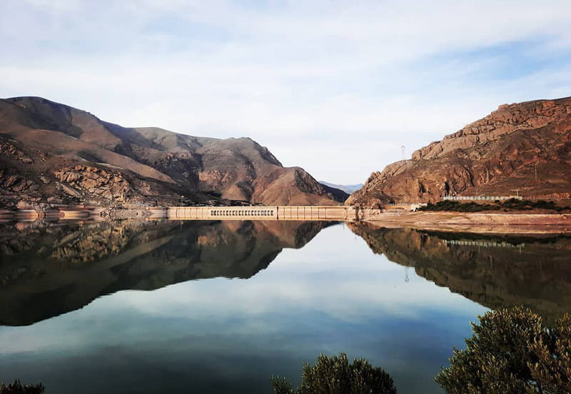 نمایی متقارن از کوهستان اطراف سد منجیل داخل آب دریاچه، منبع عکس: صفحه اینستاگرام manjil.officiah، عکاس نامشخص