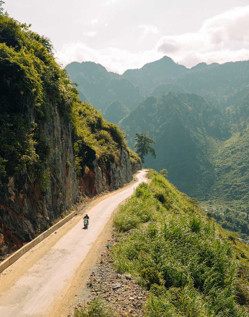 فرد موتورسوار در جاده‌ای کوهستانی و سرسبز در ویتنام 