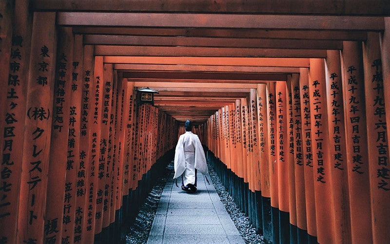 مردی با لباس ژاپنی در حال عبور از زیر طاق نارنجی