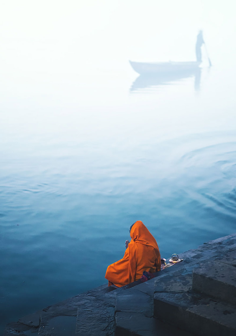 زنی با لباس نارنجی کنار آب رودخانه