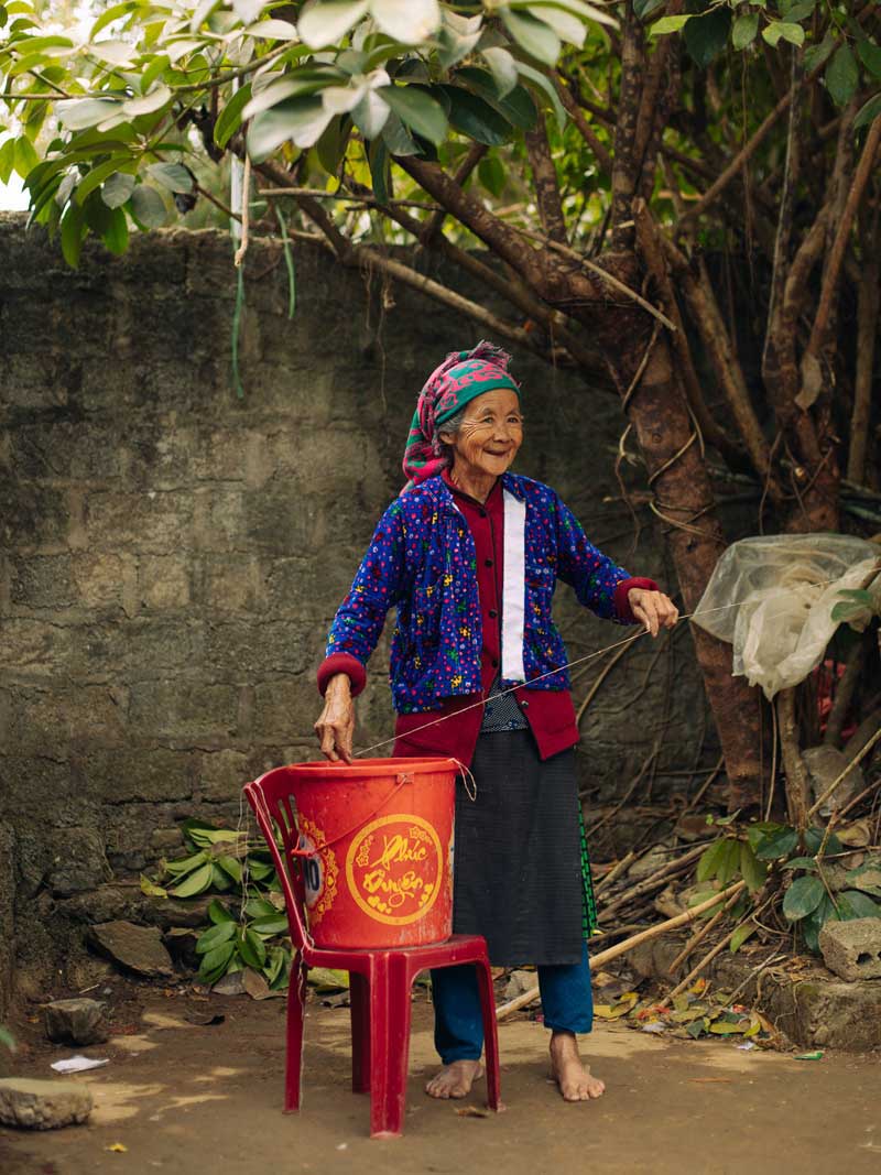 پیرزن ویتنامی با لباس رنگی و سطل به دست