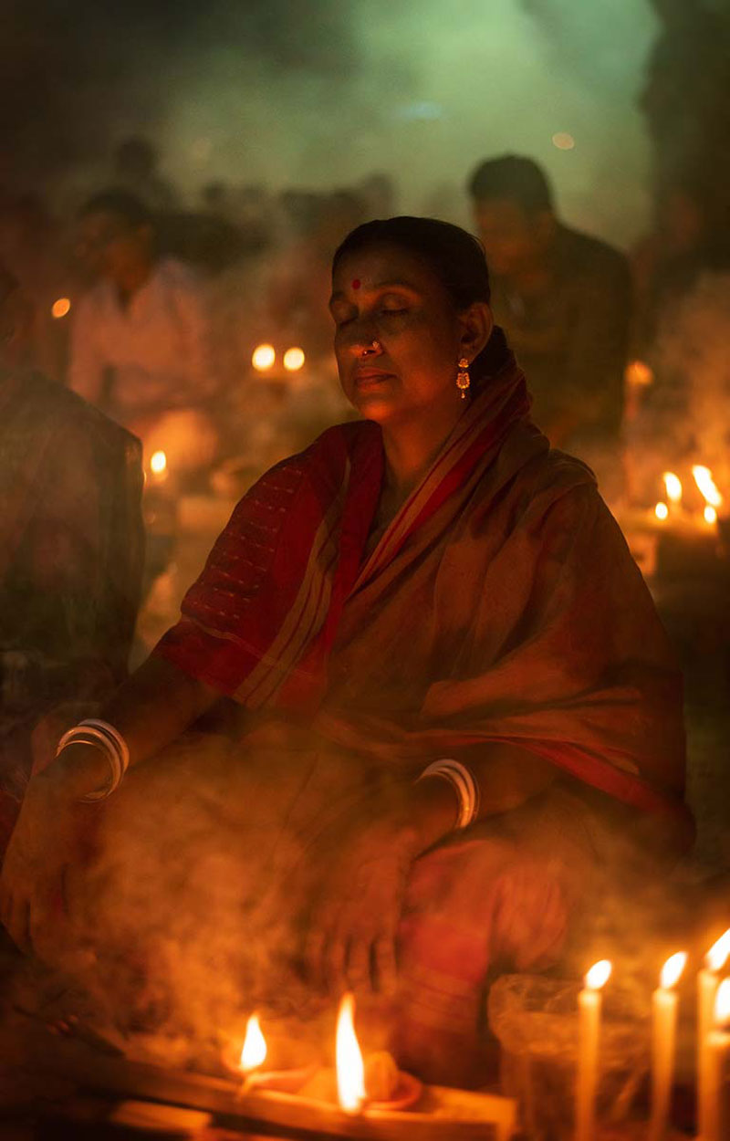 زن هندو در کنار شمع‌های روشن در فستیوال راخر اوپوپاش