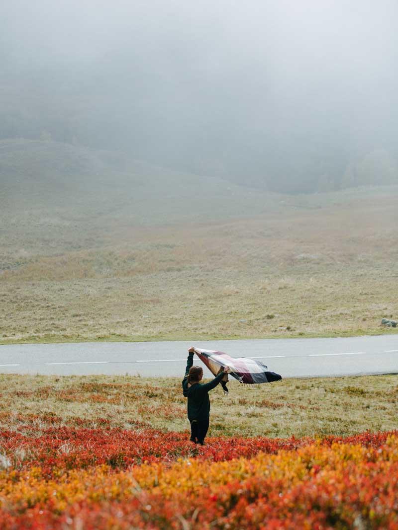 زنی در میان جاده‌ای با پوشش گیاهی پاییزی