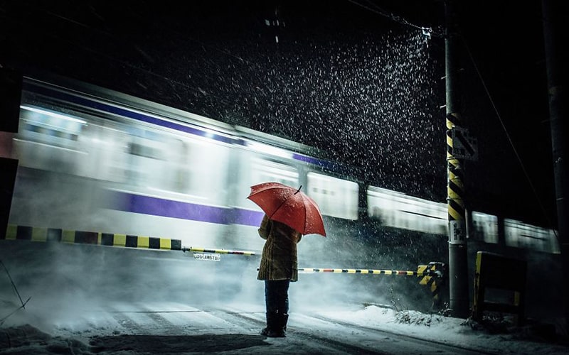 زنی با چتر قرمز در کنار قطار