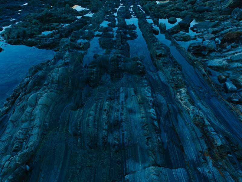 صخره‌هایی بلند با پوشش گیاهی در نور آبی رنگ