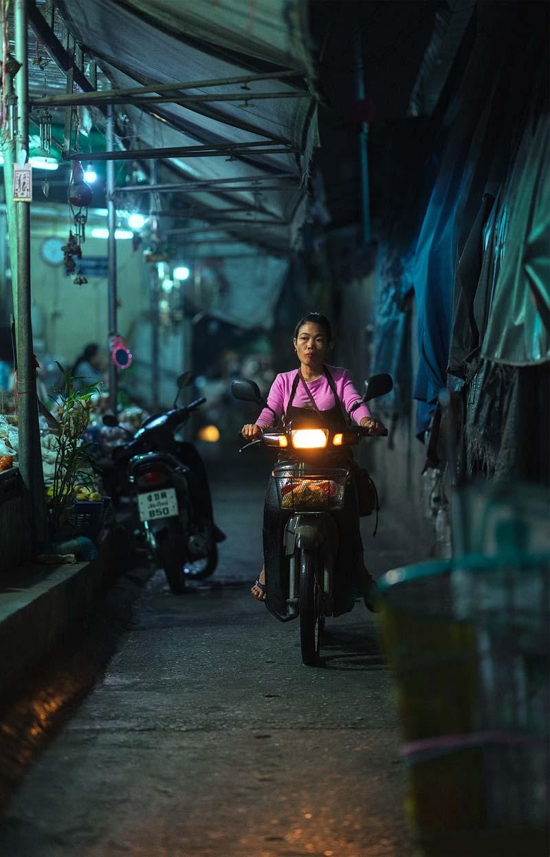 زنی با لباس صورتی و سوار بر موتور در خیابانی در شهر چیانگ مای