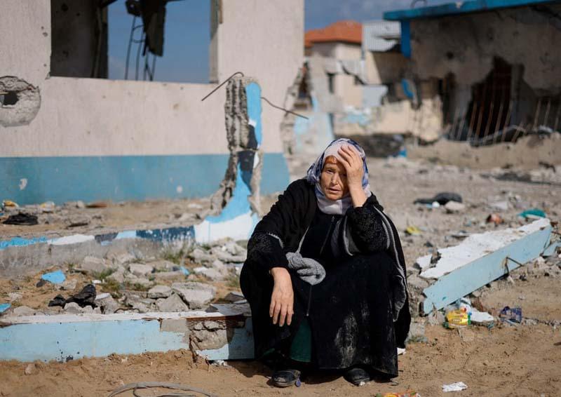 استراحت یک زن فلسطینی در کنار یک ساختمان آسیب دیده 