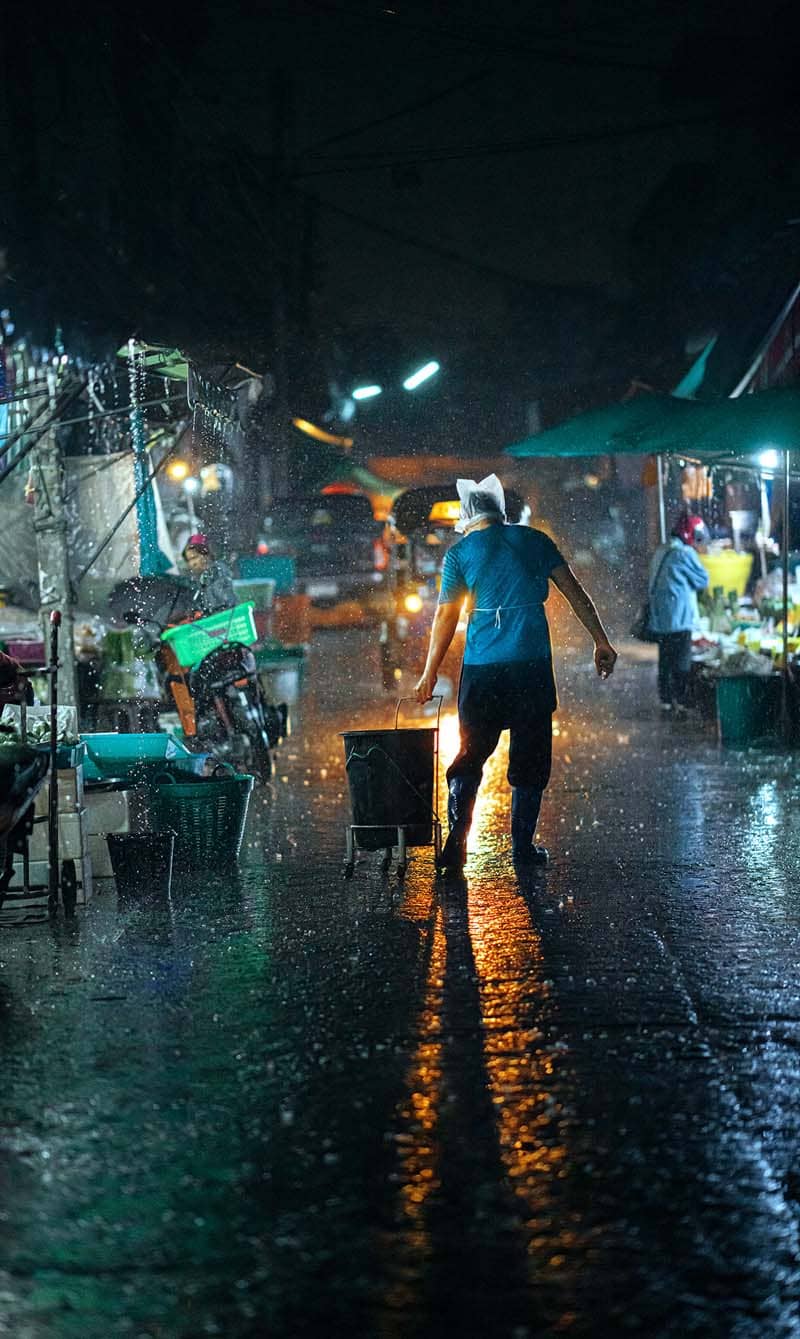 مردی در حال کشیدن یک بسته در خیابان بارانی شهر چیانگ مای