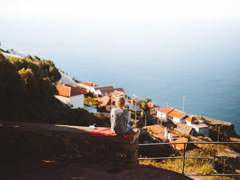 زنی نشسته روبروی بخش مسکونی جزیره مادیرا در پرتغال