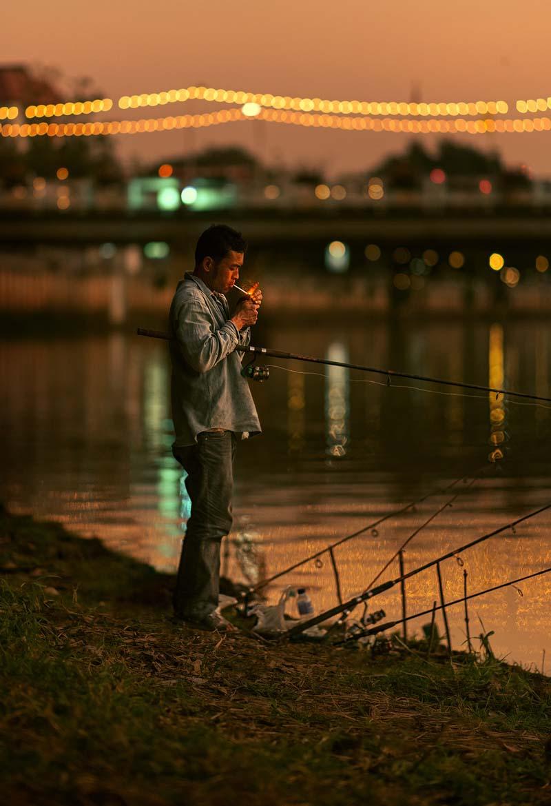 مردی در حال کشیدن سیگار کنار رودی در شهر چیانگ مای تایلند