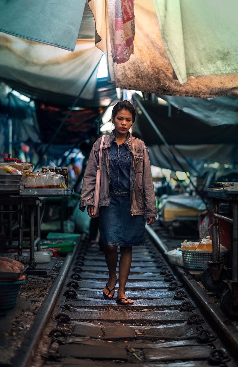 زنی در حال عبور از ریل راه آهن در بازار ریلی بانکوک 