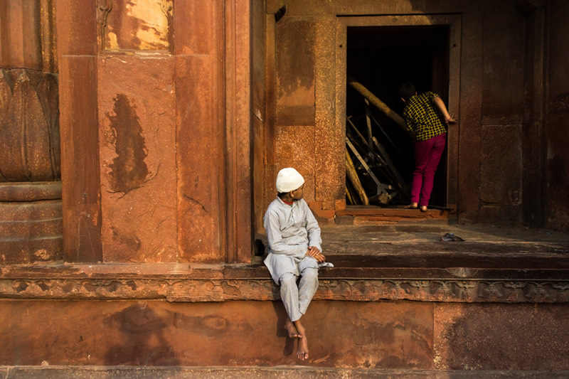 مردی با لباس سفید نشسته بر سکویی در مسجد جامع دهلی