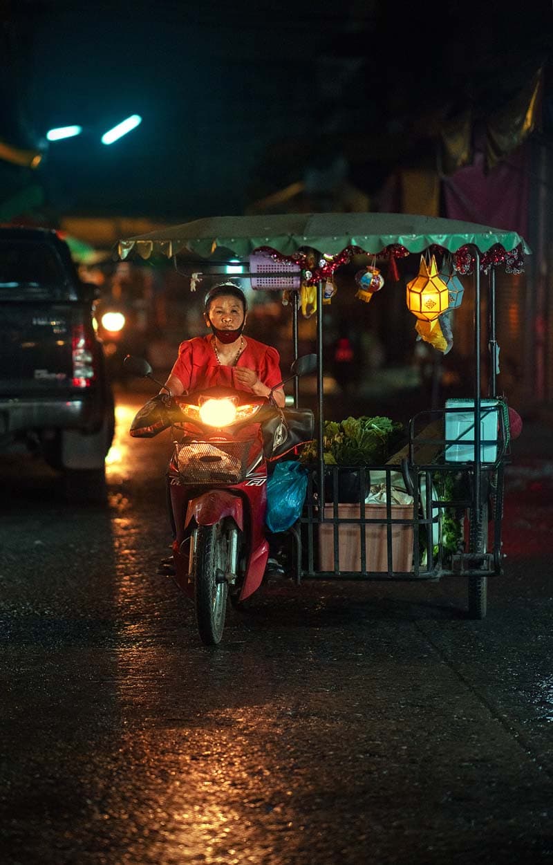 زنی روی موتور در شب بارانی شهر چیانگ مای