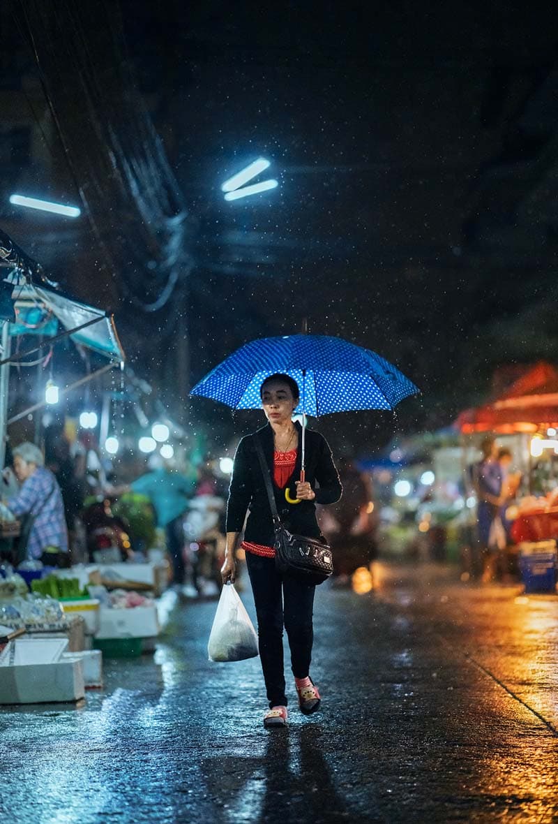 زنی با چتر در خیابان بارانی شهر چیانگ مای هنگام شب 