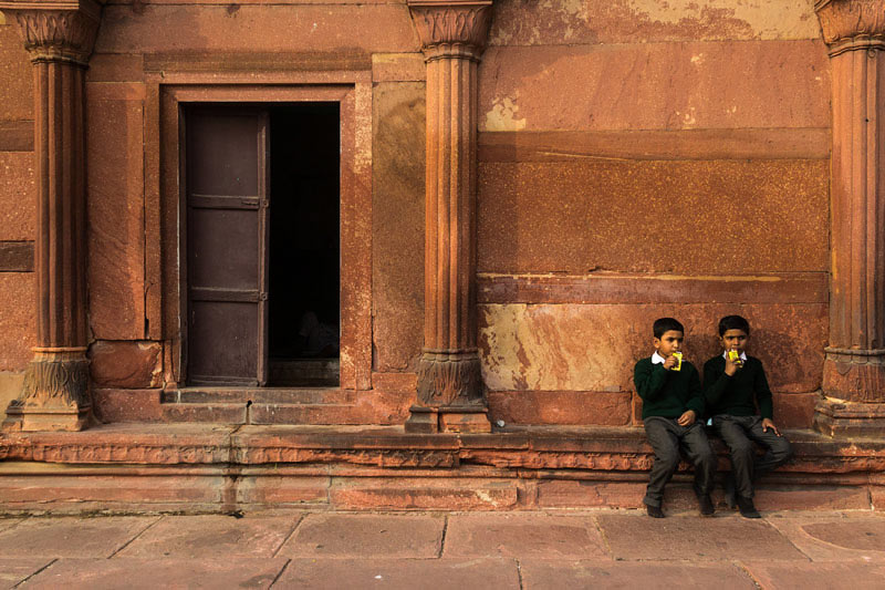دو پسر نوجوان با لباس یکسان نشسته در گوشه‌ای از مسجد جامع دهلی