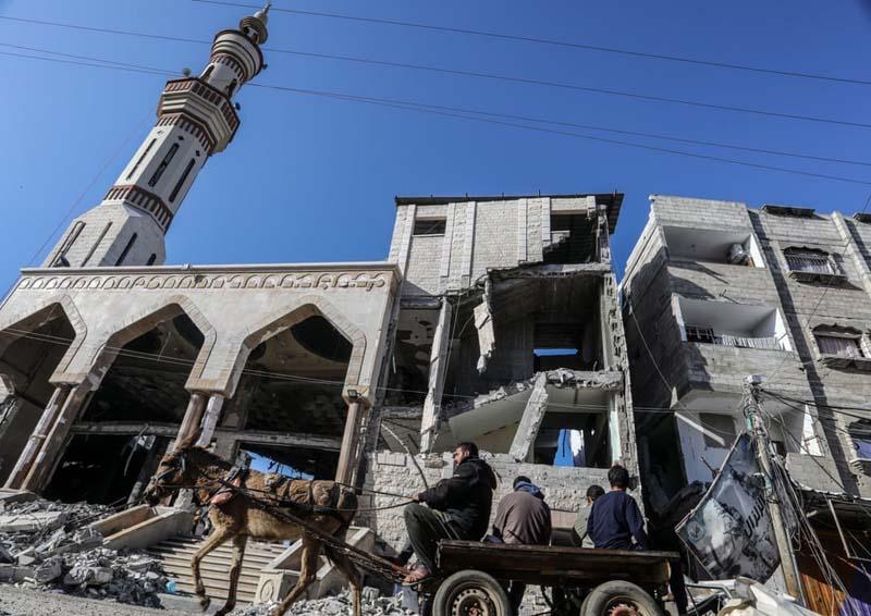 عبور فلسطینی ها از مقابل مسجد الهدی تخریب شده در جریان حملات اسرائیلی‌ها در غزه 