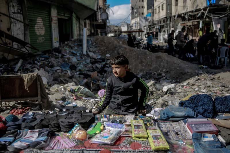 پسر فلسطینی در یک بازار خیابانی موقتی در حال فروش آنچه که در توان دارد