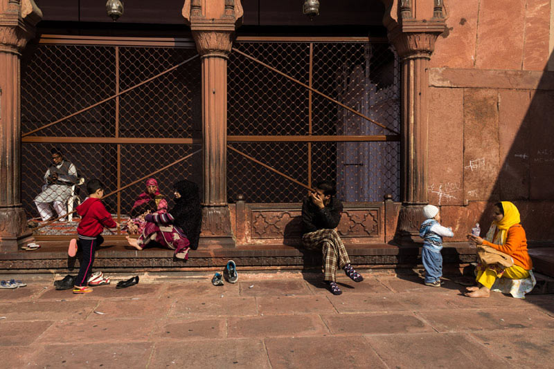 خانواده‌ها نشسته در گوشه‌ای از حیاط مسجد جامع دهلی
