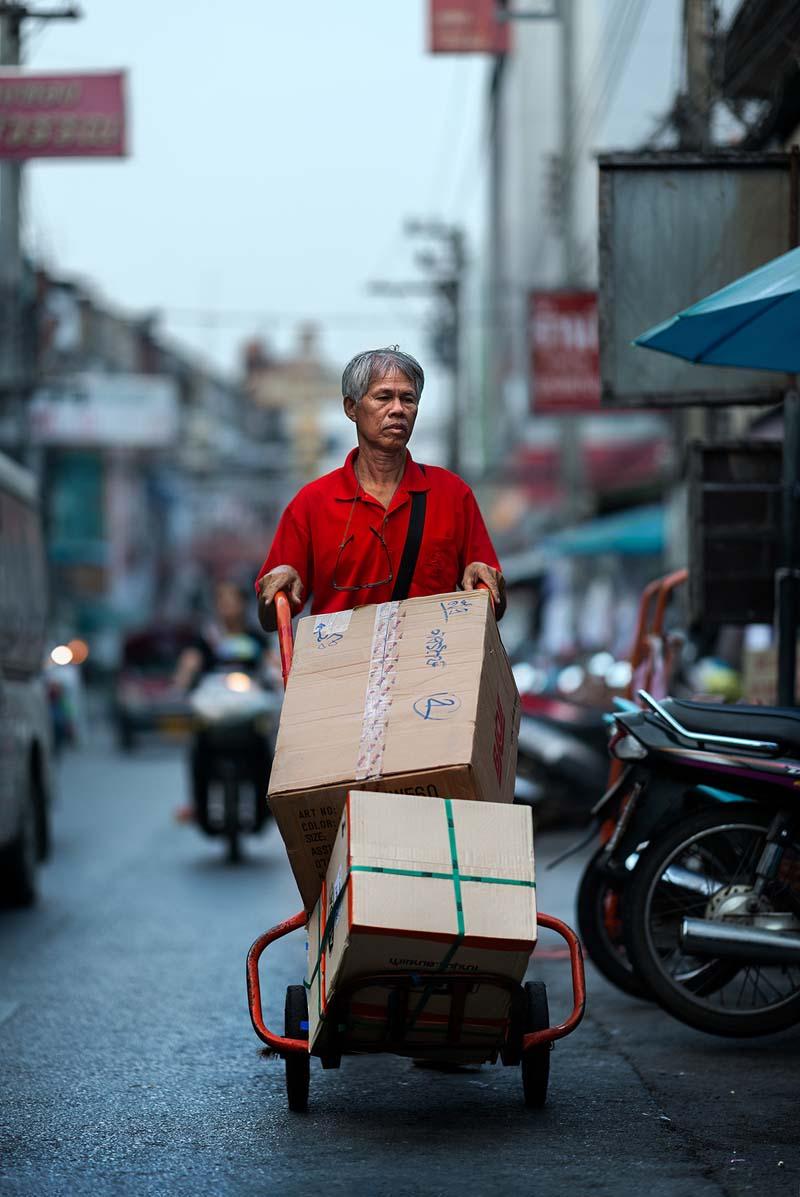 مردی در حال حمل جعبه‌های روی چرخ در شهر چیانگ مای