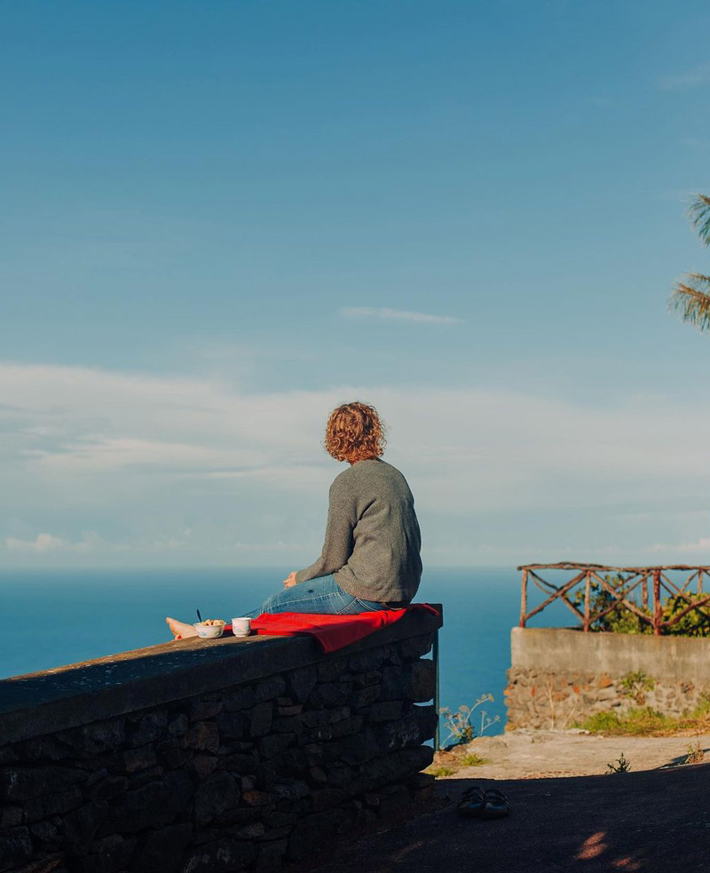 زنی نشسته بر بلندی ساختمانی در جزیره مادیرا در پرتغال