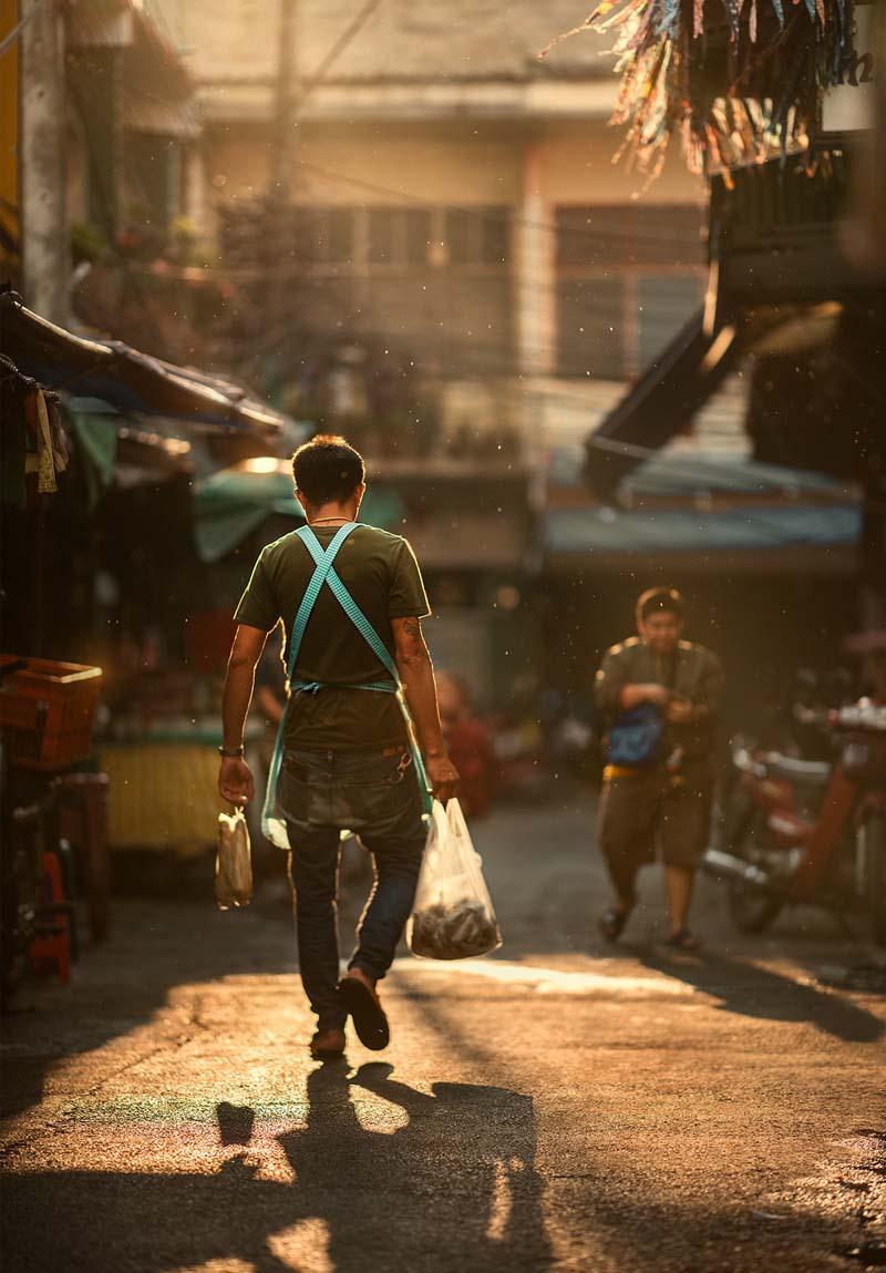 مردی در حال حمل کیسه‌های خرید در خیابانی در شهر چیانگ مای