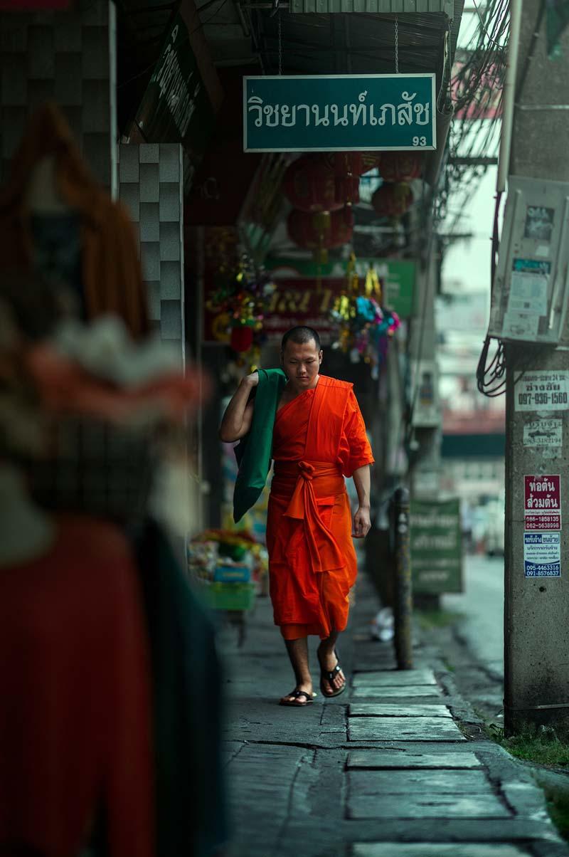 راهبی با لباس مخصوص در حال عبور از خیابانی در تایلند