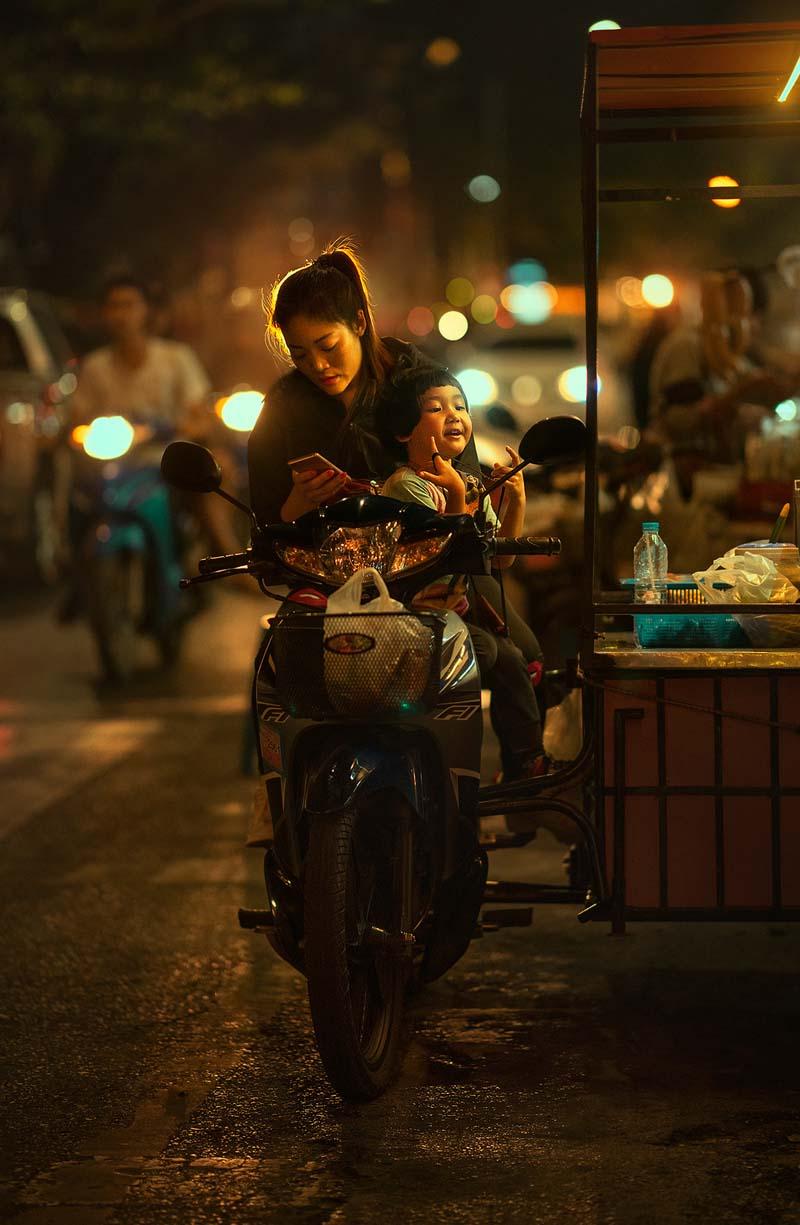 زن و کودکی روی موتور در شهر چیانگ مای هنگام شب 