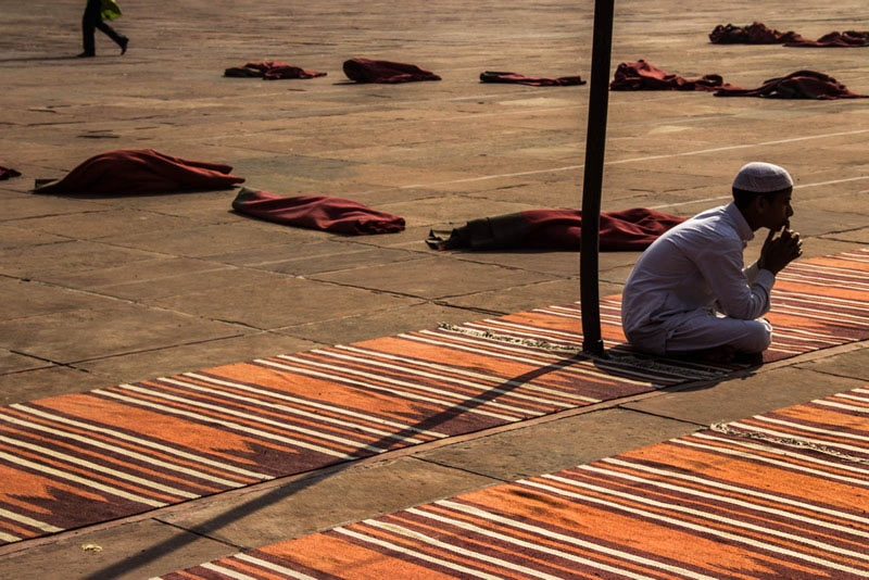 مردی نشسته بر فرش‌ در حیاط مسجد جامع دهلی