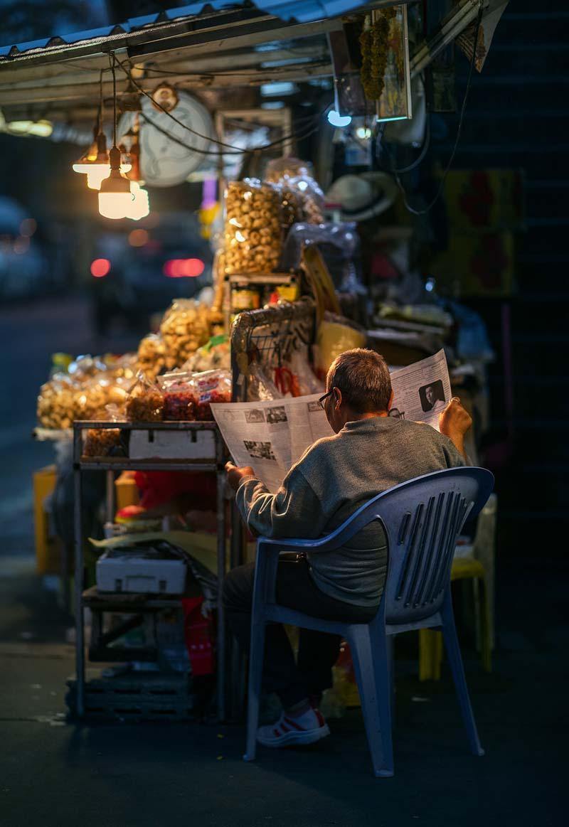 مرد تایلندی در حال خواندن روزنامه در خیابان